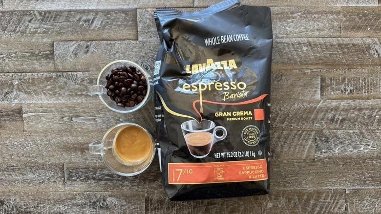 Lavazza Gran Crema bag, roasted beans and brewed espresso on a wooden table