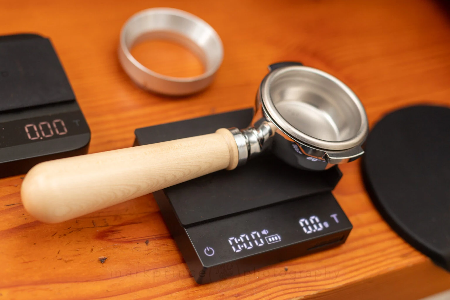 A portafilter resting on a small coffee scale on a wooden counter