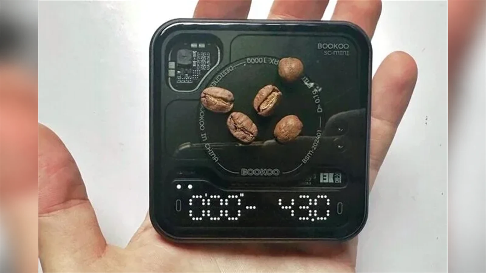 BOOKOO Themis Mini held in one hand with coffee beans on its platform