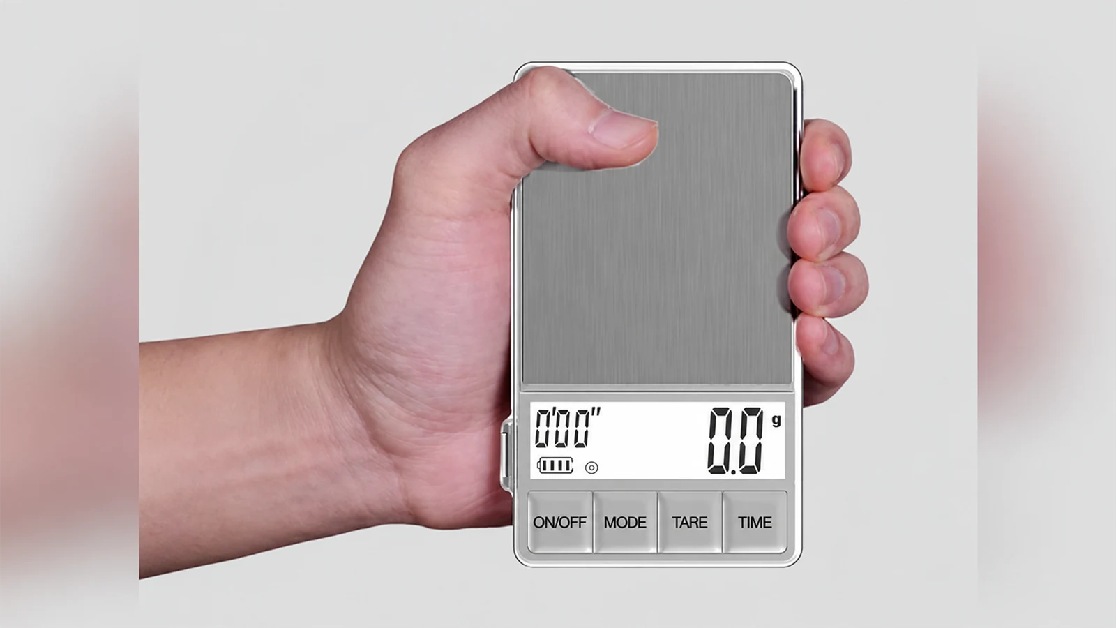 A hand holding the silver WEIGHTMAN espresso scale with its display visible