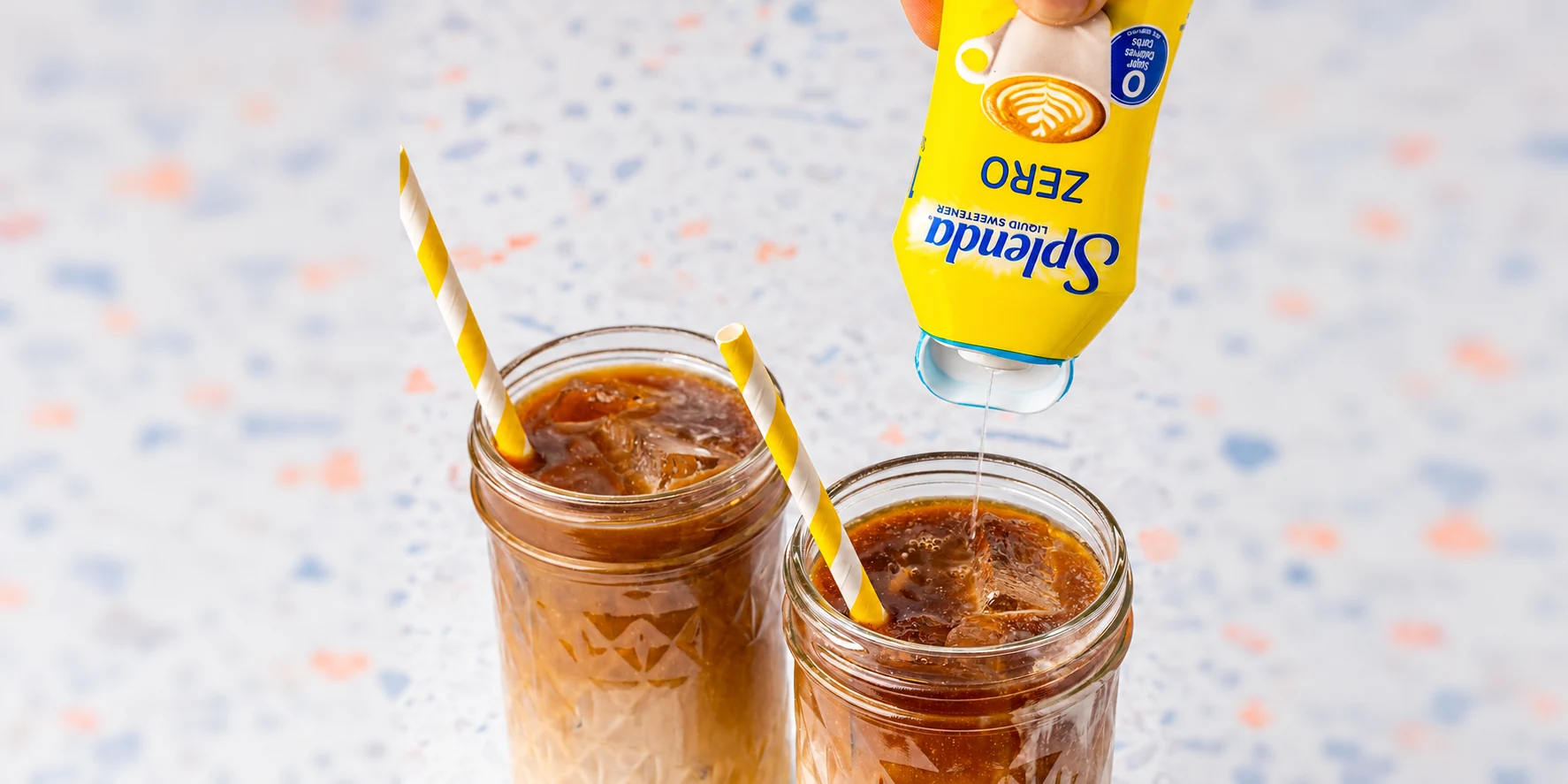 SPLENDA Original liquid sweetener being dispensed into a glass of iced coffee with milk