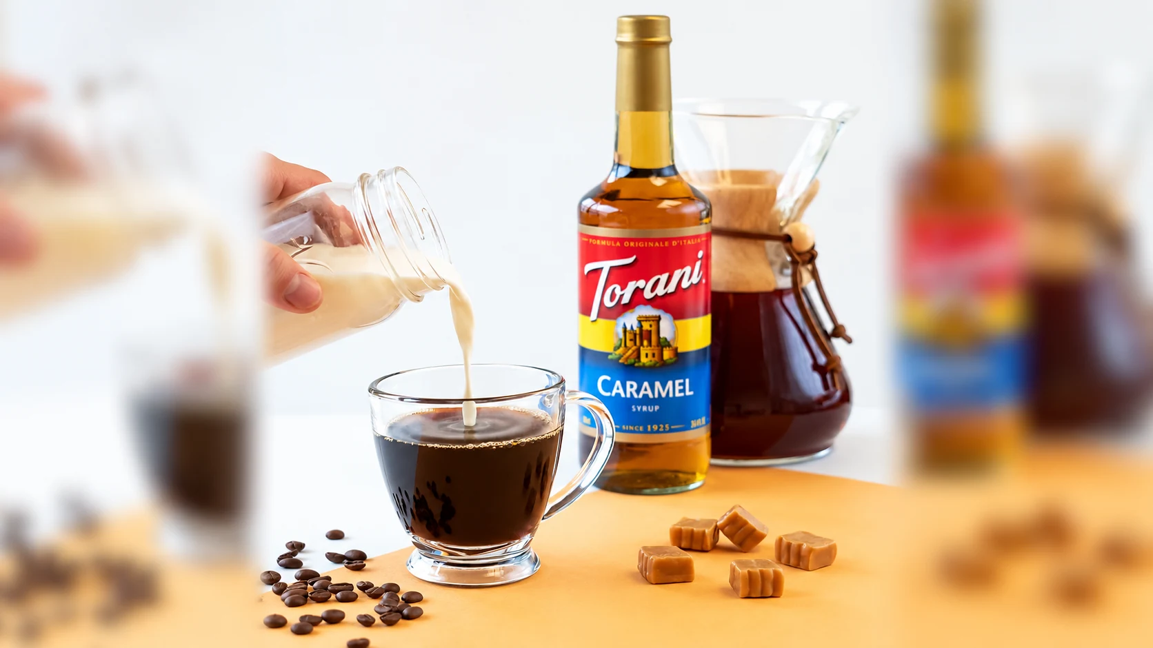 Milk being added to coffee beside Torani Caramel syrup illustrates building a flavored latte.