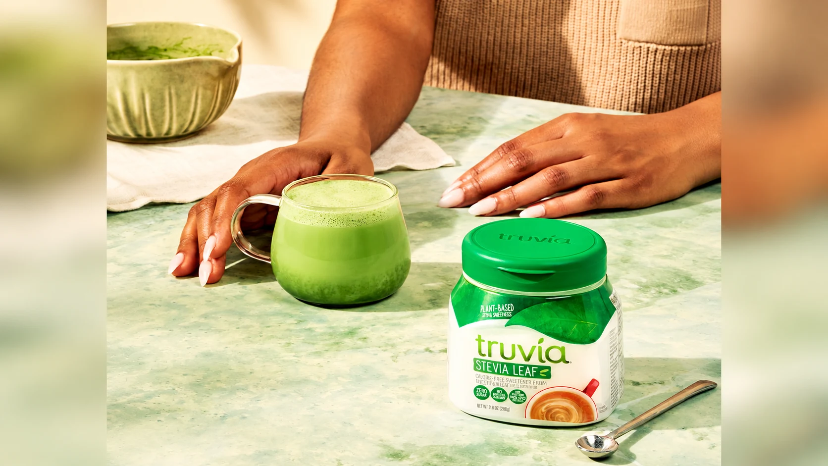 Truvia Original spoonable tub beside a green matcha drink and hands