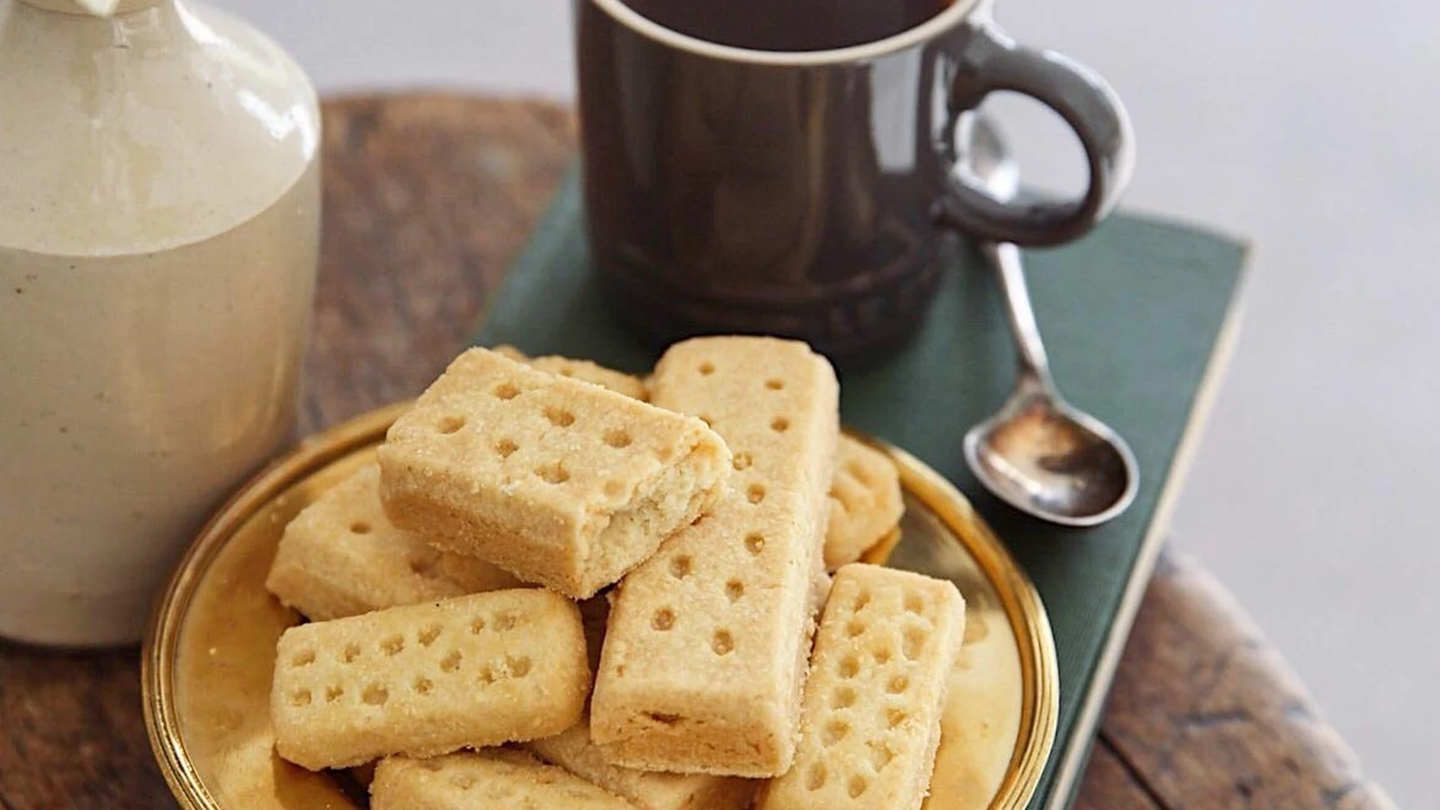 Walker's shortbread fingers on a plate beside a dark mug of coffee