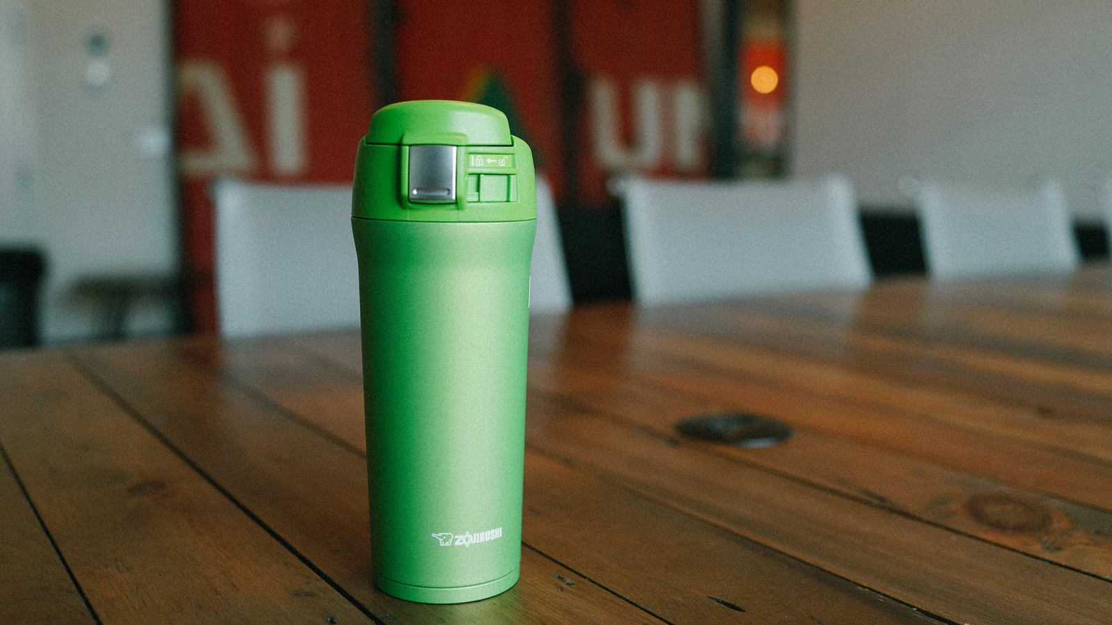 Green Zojirushi SM-YAE48 16 oz travel mug on a wooden meeting table