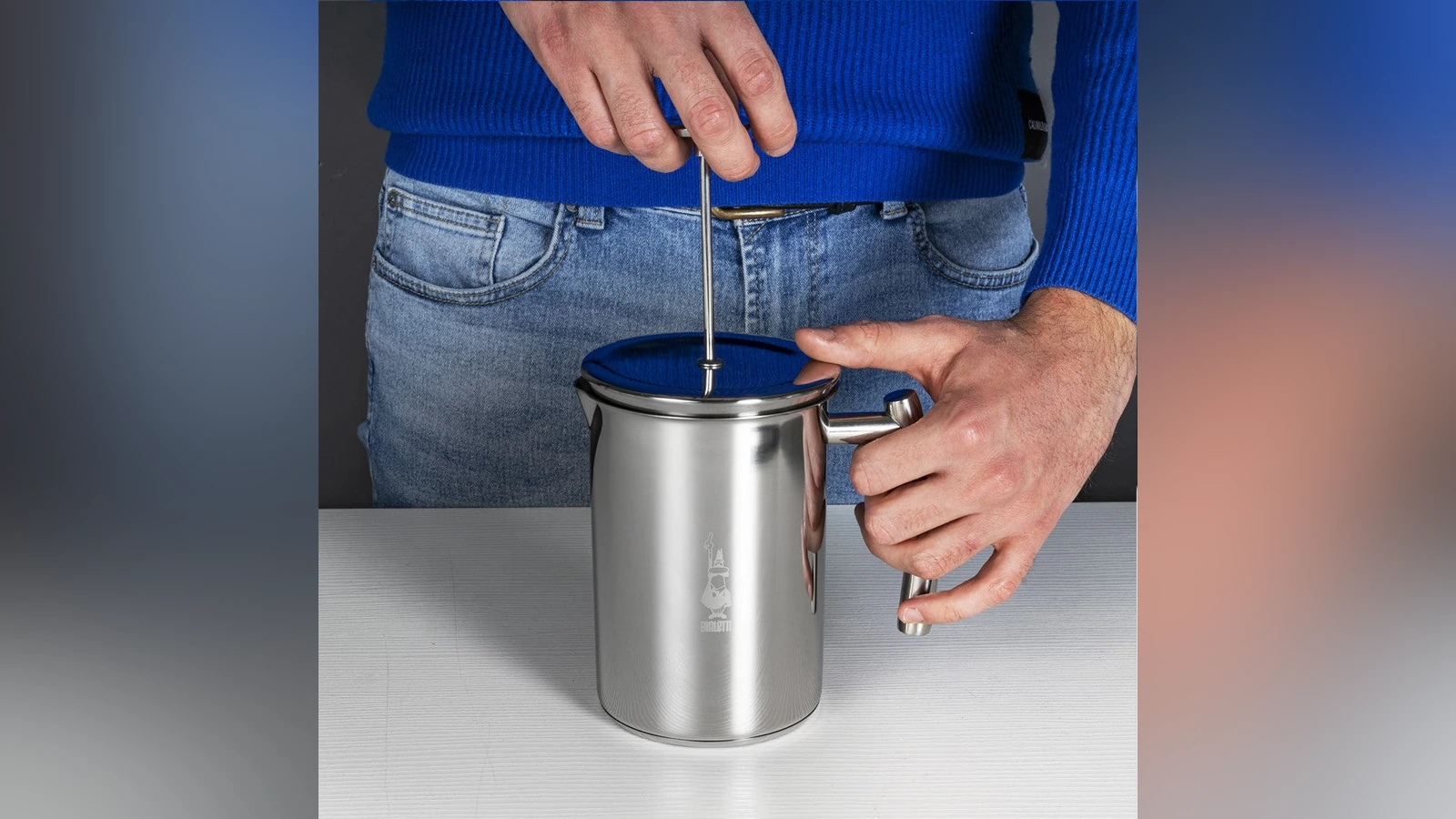 Hand operating the plunger of a stainless steel Bialetti Tuttocrema