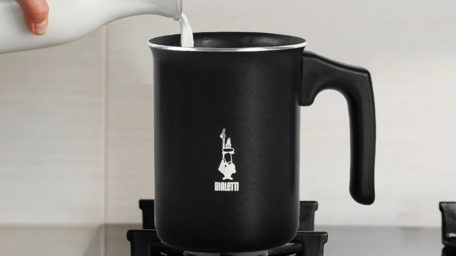 Milk being poured into the black aluminum Bialetti Tuttocrema on a stove