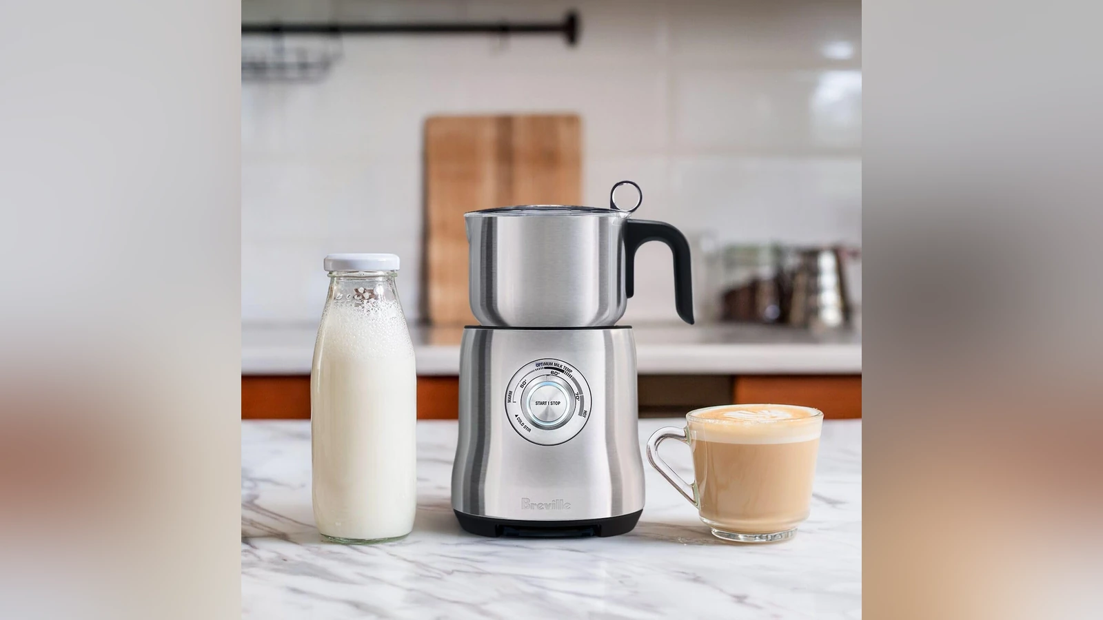 Breville Milk Café with its stainless jug, a bottle of milk and a coffee cup
