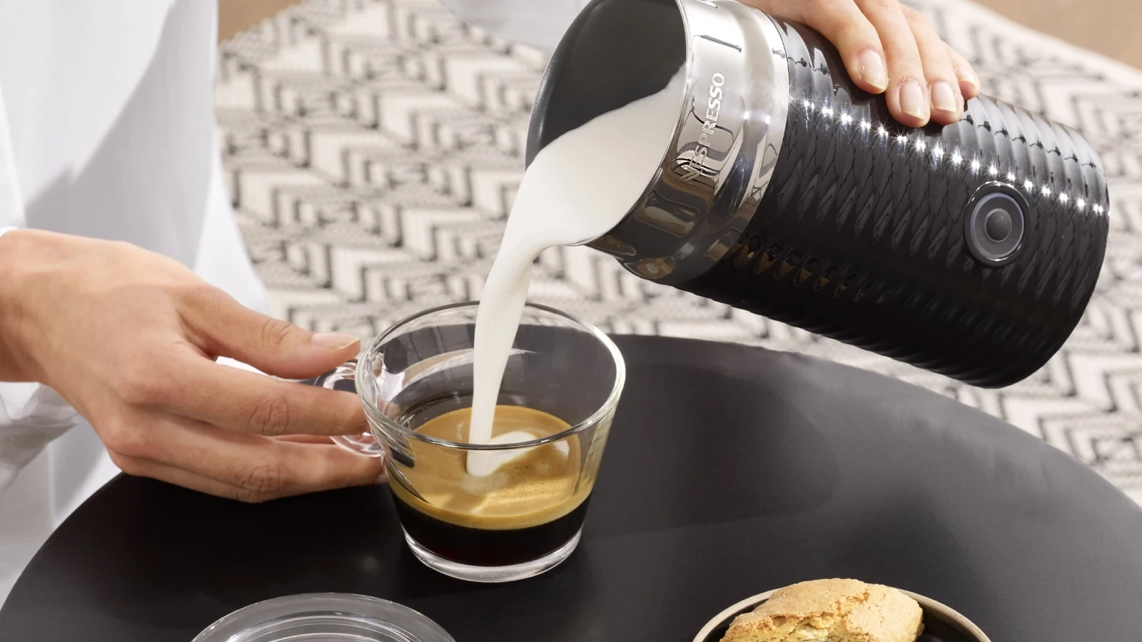 Black Nespresso Aeroccino3 pouring frothed milk into espresso