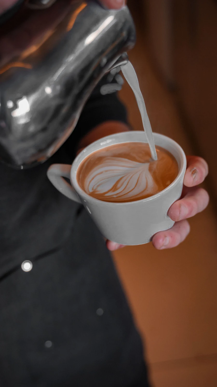 Milk pouring from a pitcher spout into a cup of espresso. Photo: Yasin Onuş / Pexels.