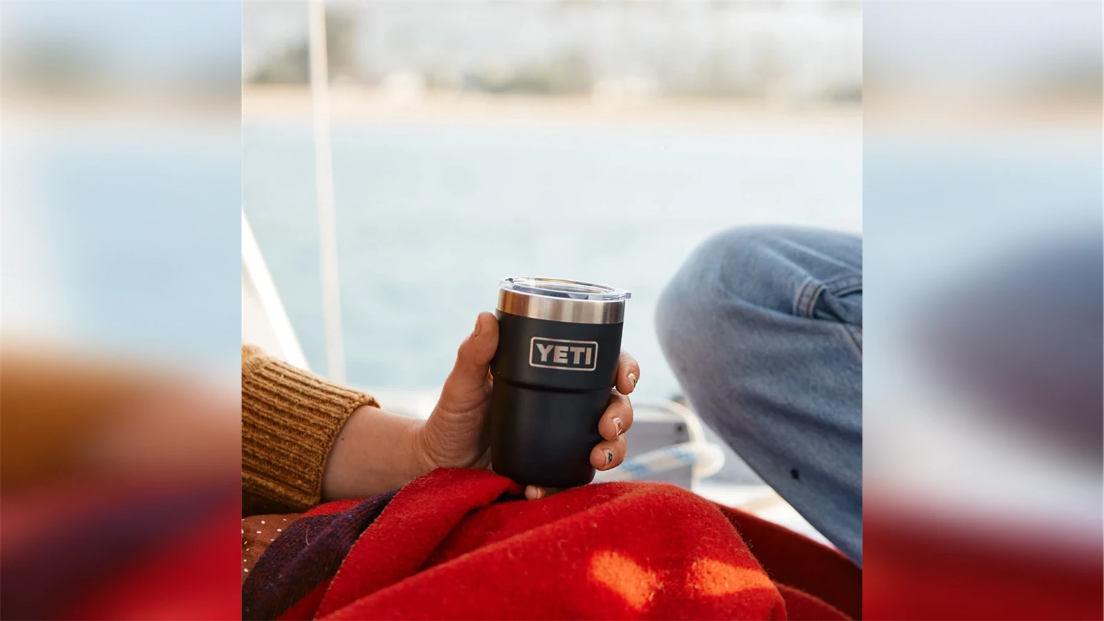 A hand holding a black YETI Rambler 8 oz Stackable Cup outdoors