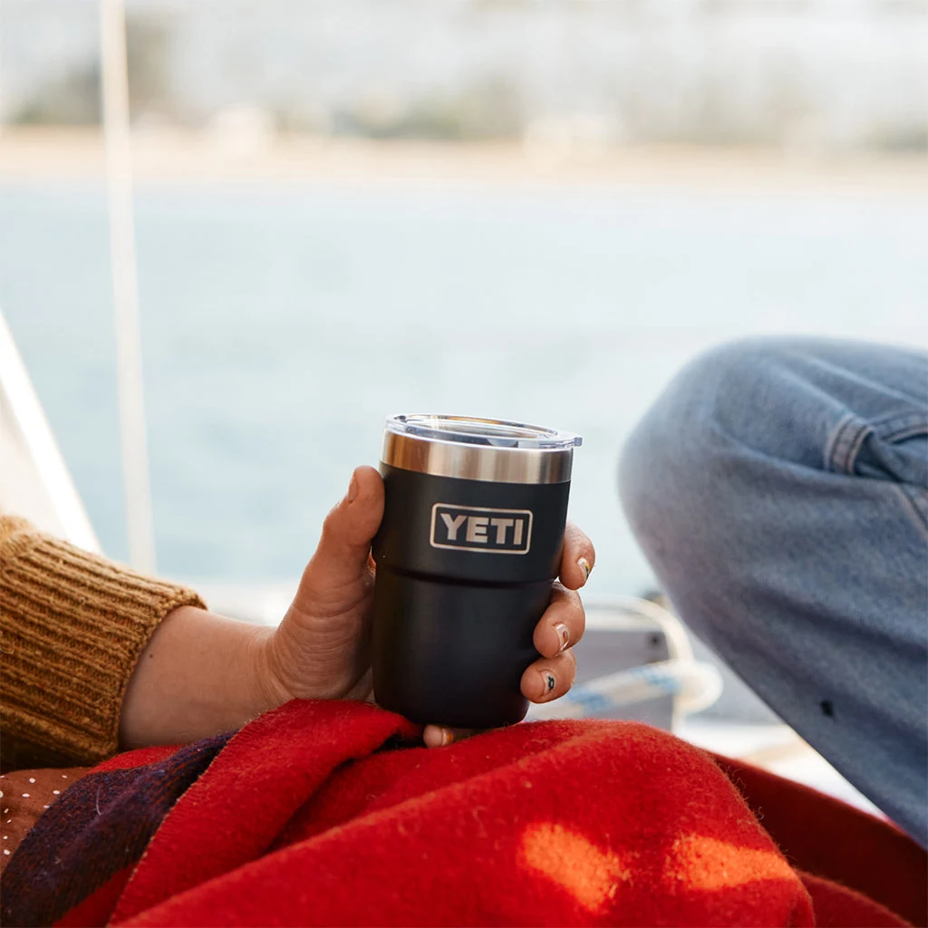 A hand holding a short YETI Rambler 8 oz cup outdoors