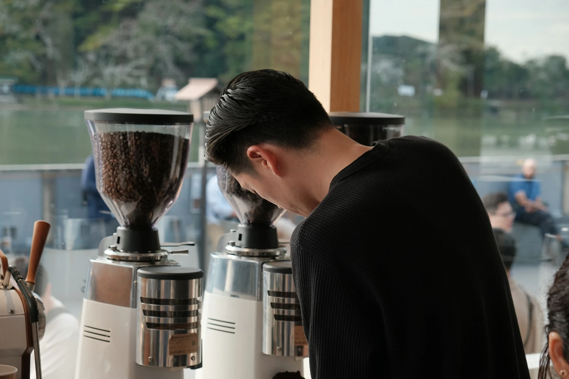 Barista adjusting a commercial espresso grinder to dial in fresh coffee beans