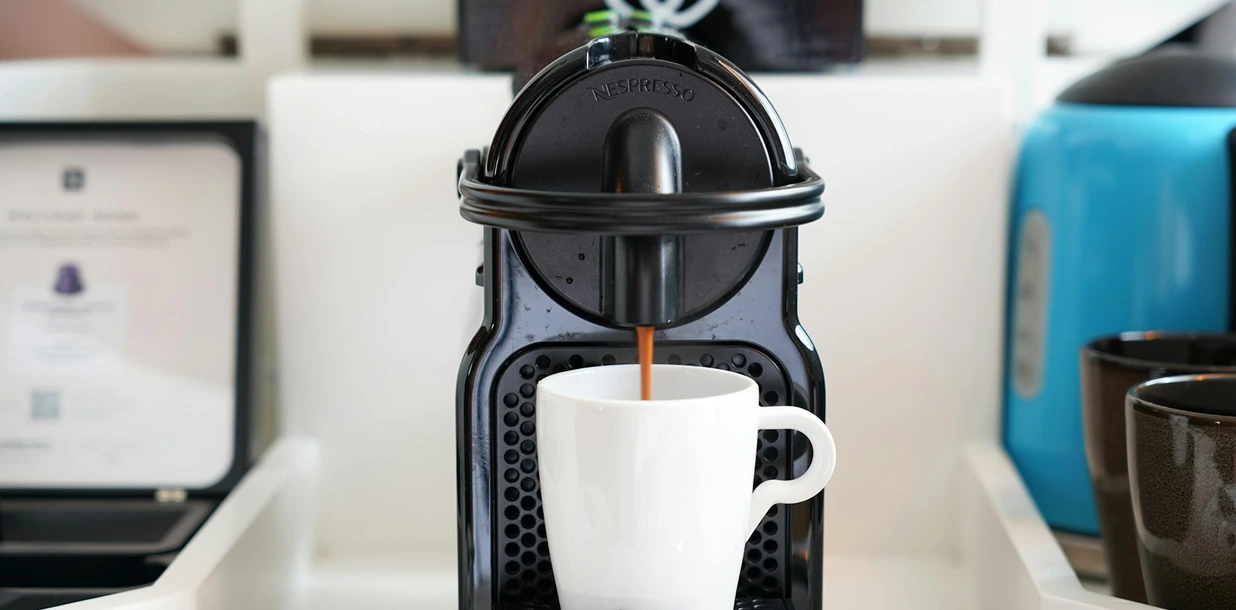 Home barista preparing espresso on a compact stainless steel machine with a 58mm portafilter and a milk pitcher