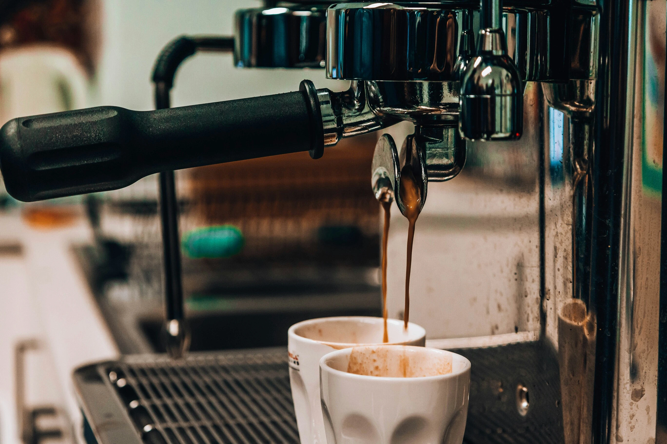 Close-up of espresso pouring from a portafilter into two demitasse cups