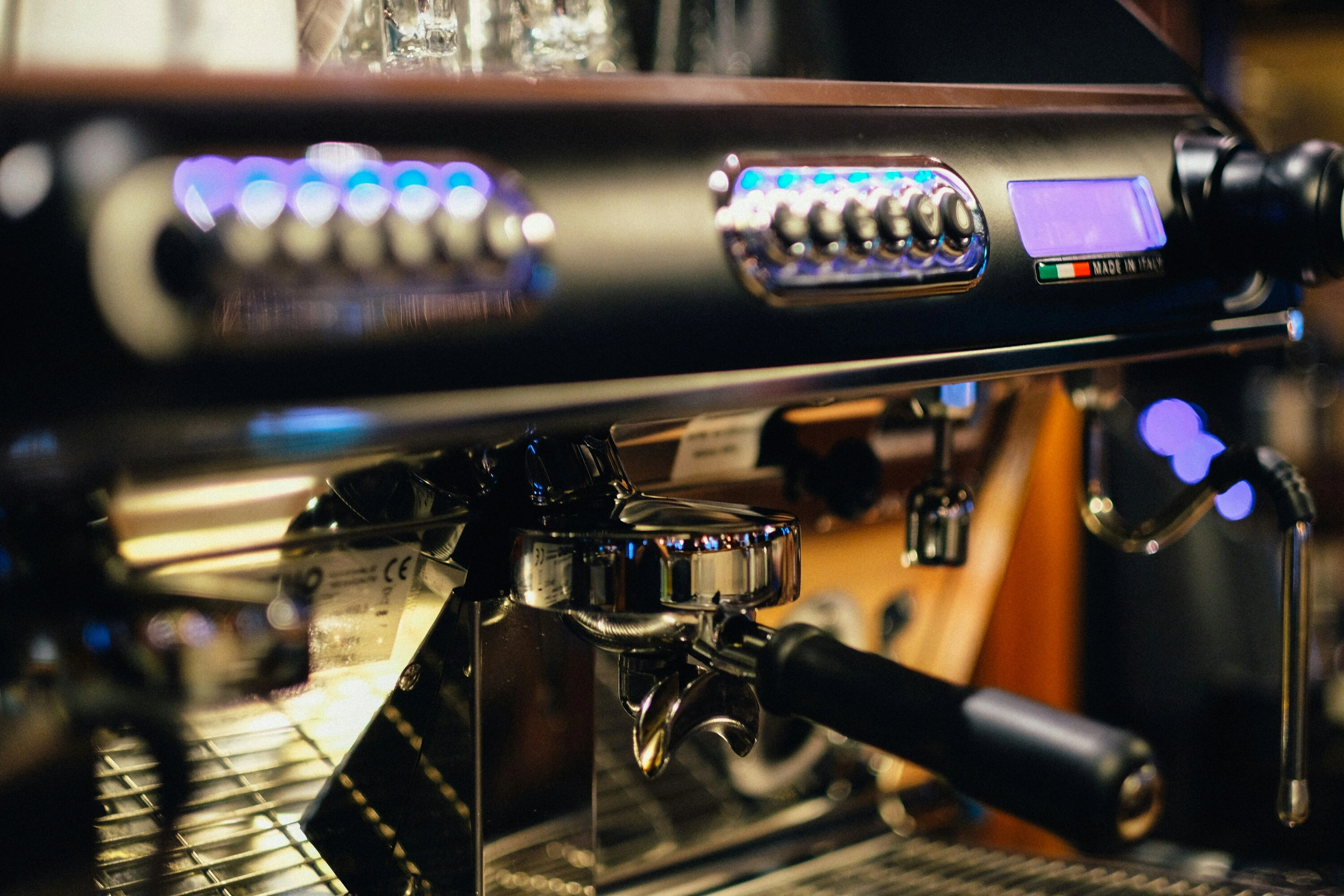 Commercial espresso machine with illuminated control panel and portafilter attached