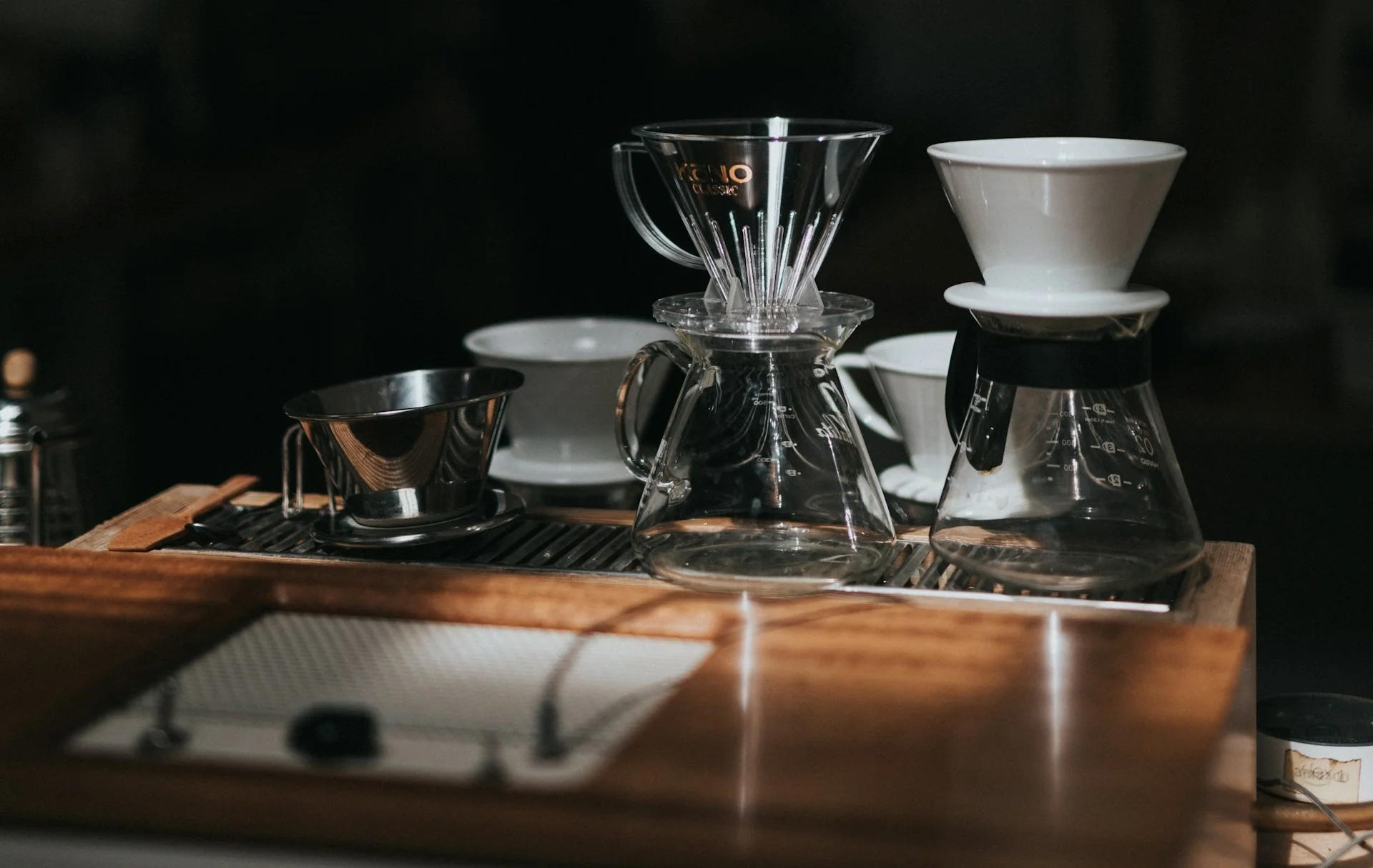 Steam wand, metal milk pitchers, and a thermometer arranged next to a home espresso machine