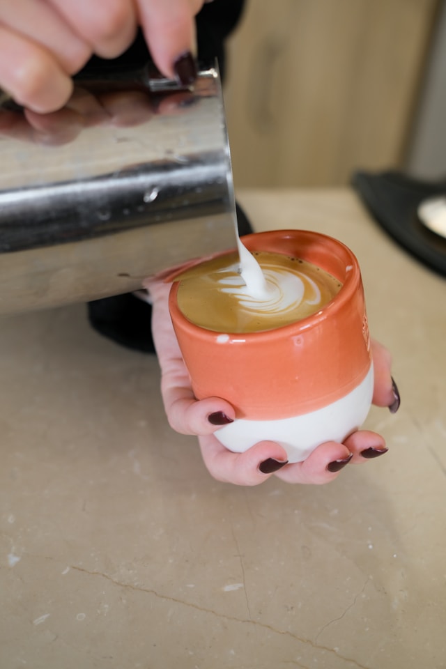 Barista steaming milk and preparing latte art at home